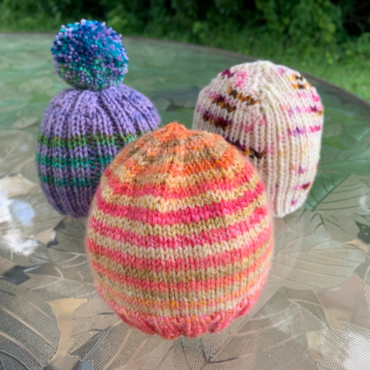 Three little hand-knit baby hats